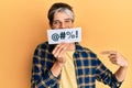 Young hispanic man covering mouth with insult message paper pointing finger to one self smiling happy and proud