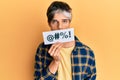 Young hispanic man covering mouth with insult message paper thinking attitude and sober expression looking self confident