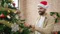 Young hispanic man decorating christmas tree at home Royalty Free Stock Photo