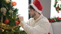 Young hispanic man decorating christmas tree at home Royalty Free Stock Photo