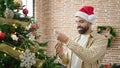 Young hispanic man decorating christmas tree at home Royalty Free Stock Photo