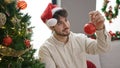 Young hispanic man decorating christmas tree at home Royalty Free Stock Photo