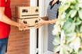 Young hispanic man delivering package to homeowner - Senior woman receiving the parcel box from the delivery worker Royalty Free Stock Photo