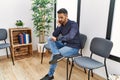 Young hispanic man desperate sitting on chair at waiting room Royalty Free Stock Photo