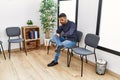 Young hispanic man desperate sitting on chair at waiting room Royalty Free Stock Photo