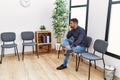 Young hispanic man desperate sitting on chair at waiting room Royalty Free Stock Photo