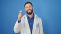 Young hispanic man doctor holding pills bottle over isolated blue background Royalty Free Stock Photo