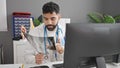 Young hispanic man doctor looking xray using computer at clinic Royalty Free Stock Photo