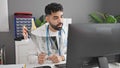 Young hispanic man doctor looking xray using computer at clinic Royalty Free Stock Photo