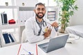 Young hispanic man doctor smiling confident holding glasses at clinic Royalty Free Stock Photo