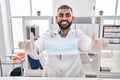 Young hispanic man doctor smiling confident holding medical mask at clinic Royalty Free Stock Photo