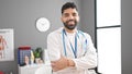 Young hispanic man doctor smiling confident standing with arms crossed gesture at clinic Royalty Free Stock Photo