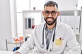 Young hispanic man doctor smiling confident standing on table at clinic Royalty Free Stock Photo