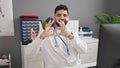 Young hispanic man doctor smiling doing heart gesture with hands at clinic Royalty Free Stock Photo