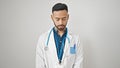 Young hispanic man doctor standing with serious expression looking down over isolated white background Royalty Free Stock Photo