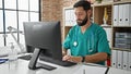 Young hispanic man doctor using computer working at the clinic Royalty Free Stock Photo