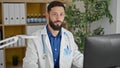 Young hispanic man doctor using computer working at the clinic Royalty Free Stock Photo