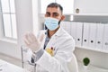 Young hispanic man doctor wearing medical mask wearing gloves at clinic Royalty Free Stock Photo