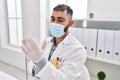 Young hispanic man doctor wearing medical mask wearing gloves at clinic Royalty Free Stock Photo