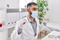 Young hispanic man doctor wearing medical mask holding stethoscope at clinic Royalty Free Stock Photo