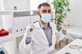 Young hispanic man doctor wearing medical mask holding stethoscope at clinic Royalty Free Stock Photo