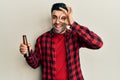 Young hispanic man drinking a bottle of beer smiling happy doing ok sign with hand on eye looking through fingers Royalty Free Stock Photo