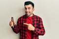 Young hispanic man drinking a bottle of beer smiling happy pointing with hand and finger Royalty Free Stock Photo