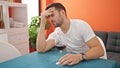 Young hispanic man drinking glass of wine depressed at dinning room Royalty Free Stock Photo