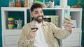 Young hispanic man drinking glass of wine having video call at dinning room Royalty Free Stock Photo