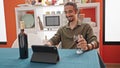 Young hispanic man drinking glass of wine watching video on touchpad at dinning room Royalty Free Stock Photo