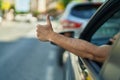 Young Hispanic Man Driving Car Doing Ok Gesture With Thumb Up At Street