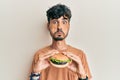 Young hispanic man eating a tasty classic burger puffing cheeks with funny face