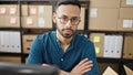 Young hispanic man ecommerce business looking serious at the camera at office Royalty Free Stock Photo