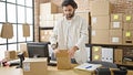 Young hispanic man ecommerce business worker packing cardboard box at office Royalty Free Stock Photo