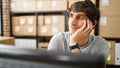 Young hispanic man ecommerce business worker sitting on table thinking at office Royalty Free Stock Photo