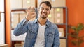 Young hispanic man ecommerce business worker standing with arms crossed gesture doing ok gesture at office Royalty Free Stock Photo