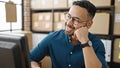 Young hispanic man ecommerce business worker thinking at office Royalty Free Stock Photo
