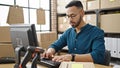 Young hispanic man ecommerce business worker typing on computer at office Royalty Free Stock Photo