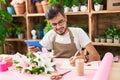 Young hispanic man florist using touchpad writing on notebook at flower shop Royalty Free Stock Photo