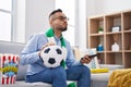 Young hispanic man football hooligan holding ball supporting team looking at the camera blowing a kiss being lovely and sexy