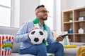 Young hispanic man football hooligan holding ball supporting team smiling with a happy and cool smile on face Royalty Free Stock Photo