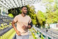 Young hispanic man with headphones running in stadium in the morning, male listening to music and audio books online Royalty Free Stock Photo