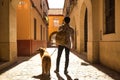 Young Hispanic man on his back with his dog holding the leash walking on a sunny street at sunset. Concept animals, dogs, love, Royalty Free Stock Photo