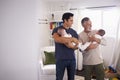 Young Hispanic man and his senior father holding his two baby boys at home Royalty Free Stock Photo