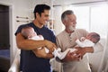 Young Hispanic man and his senior father holding his two baby boys at home Royalty Free Stock Photo