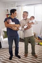 Young Hispanic man and his senior father holding his two baby boys at home, vertical Royalty Free Stock Photo