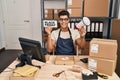 Young hispanic man holding black friday banner small commerce winking looking at the camera with sexy expression, cheerful and Royalty Free Stock Photo