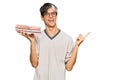 Young hispanic man holding books smiling happy pointing with hand and finger to the side Royalty Free Stock Photo