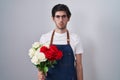 Young hispanic man holding bouquet of white and red roses skeptic and nervous, frowning upset because of problem Royalty Free Stock Photo