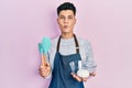 Young hispanic man holding bread dough and cooking tools making fish face with mouth and squinting eyes, crazy and comical